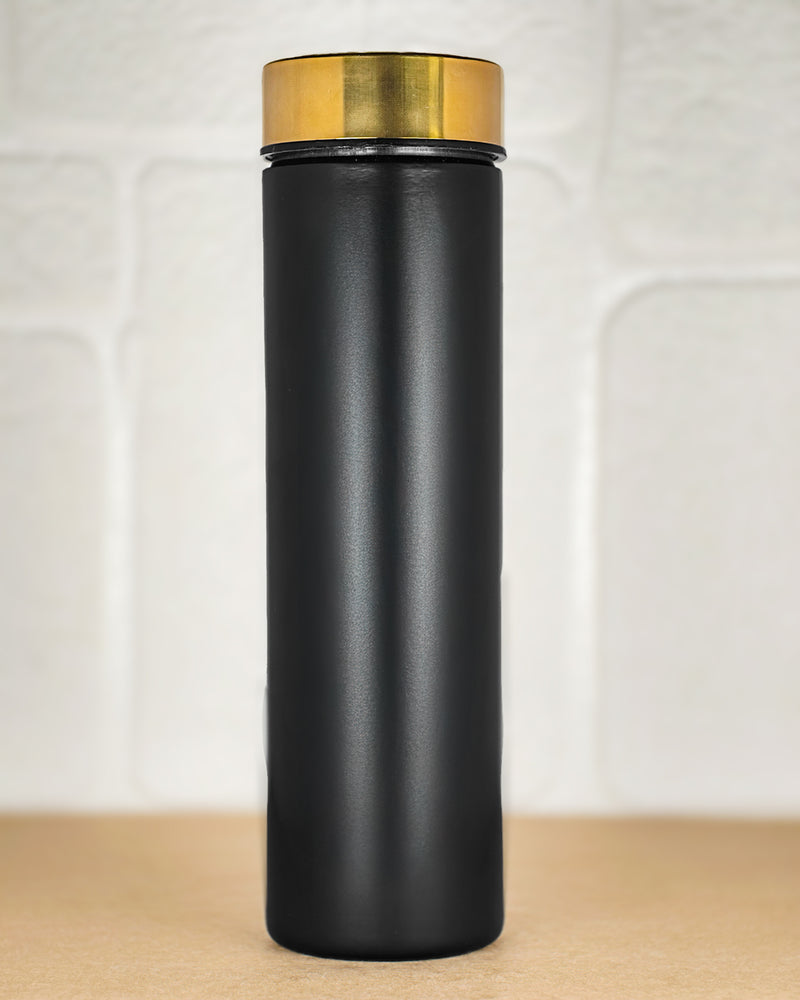 Black thermos with gold lid on a wooden surface
