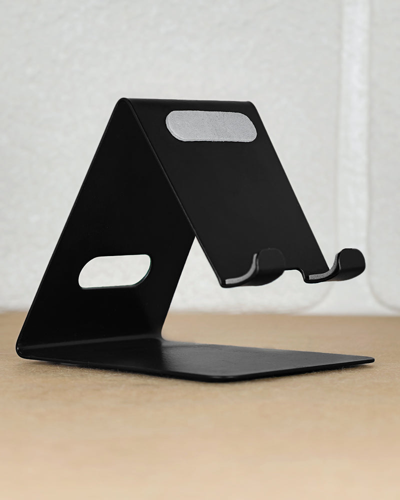 Black phone stand on a wooden surface with a light gray background