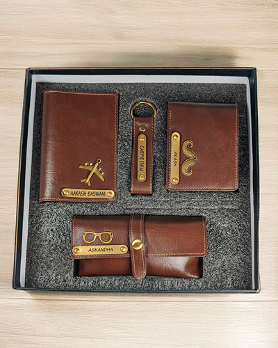 Set of brown leather wallets and keychain with gold accents in a box on a wooden surface