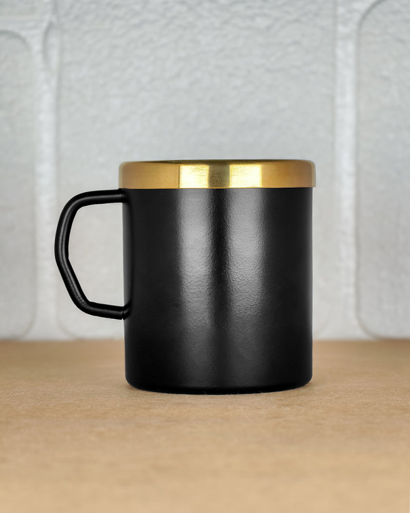 Black mug with a gold rim on a wooden surface