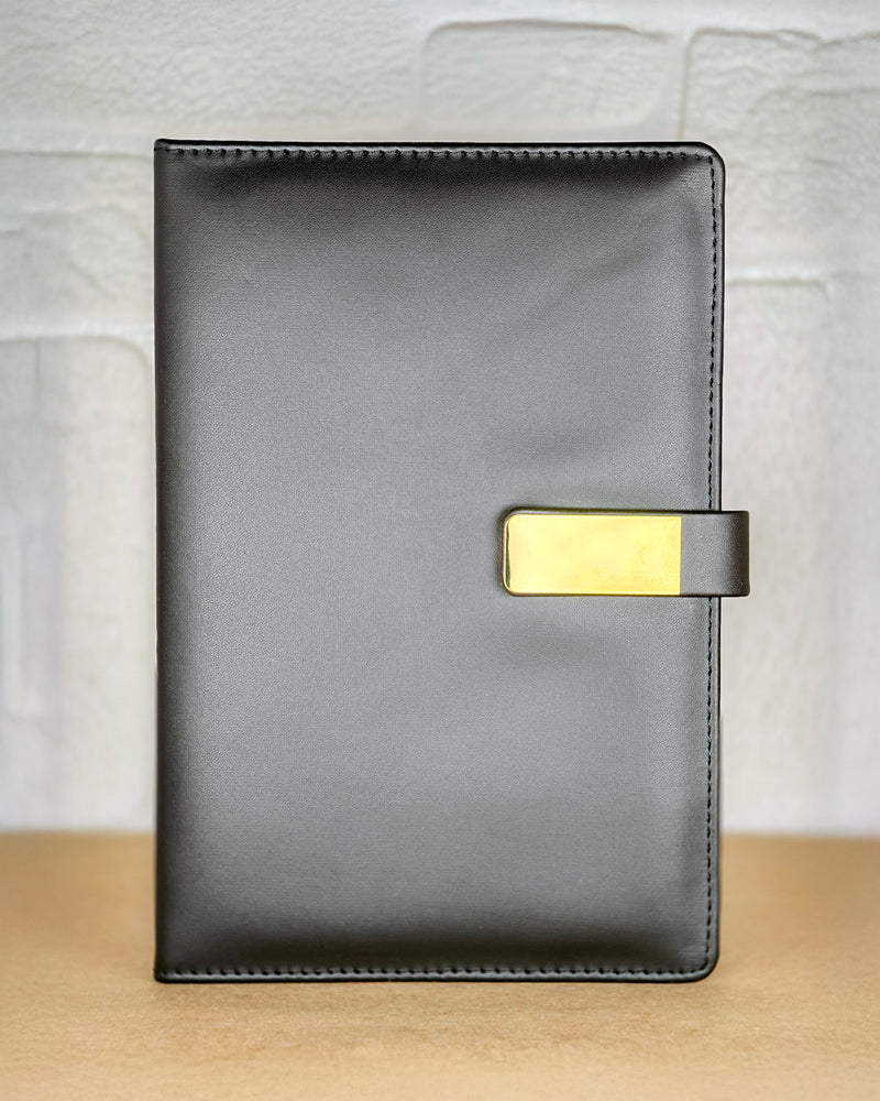 Black leather notebook with a gold buckle on a light wooden surface.