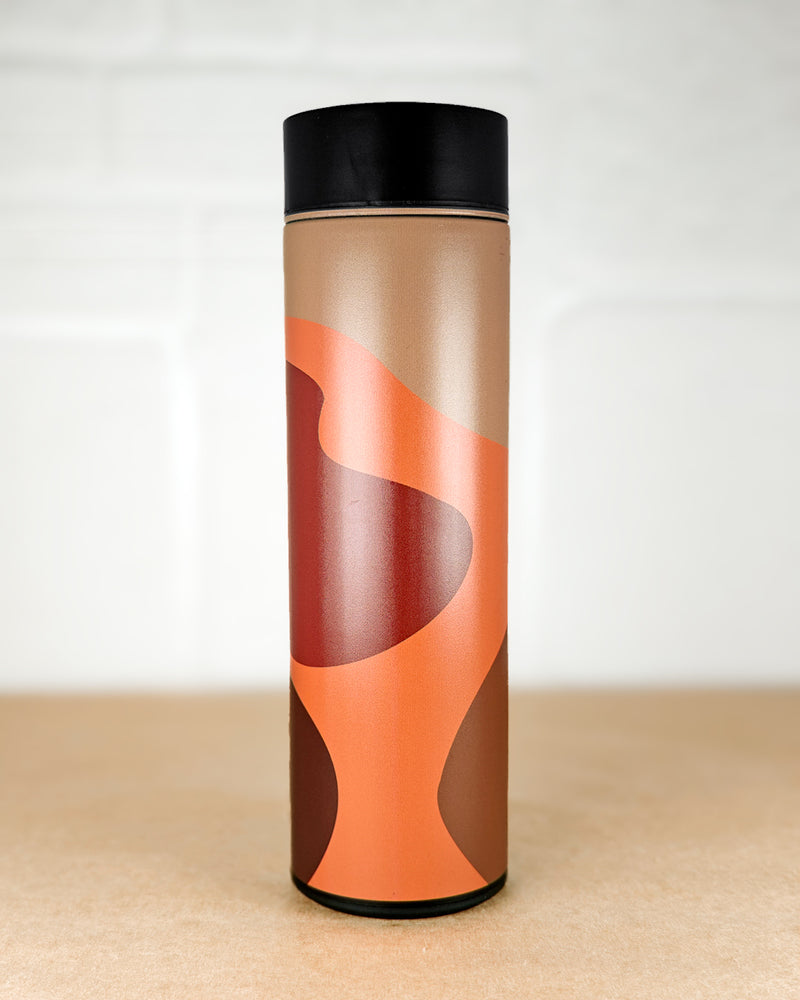 Tumbler with brown and orange design on a beige surface