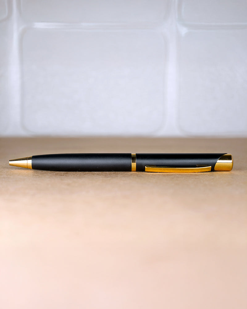 Black and gold pen on a beige surface with a white tiled background