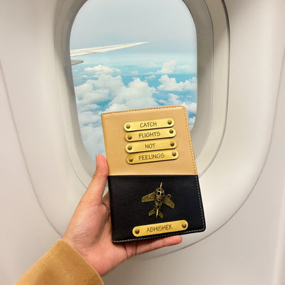 A person holding a dual tone black and beige passport cover with personalized text and a logo, while on an airplane with a cloudy sky outside the window.
