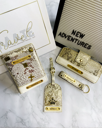 A set of travel accessories including a passport cover, luggage tag, keychain, and sunglass cover, mostly in gold color, displayed against a white background.