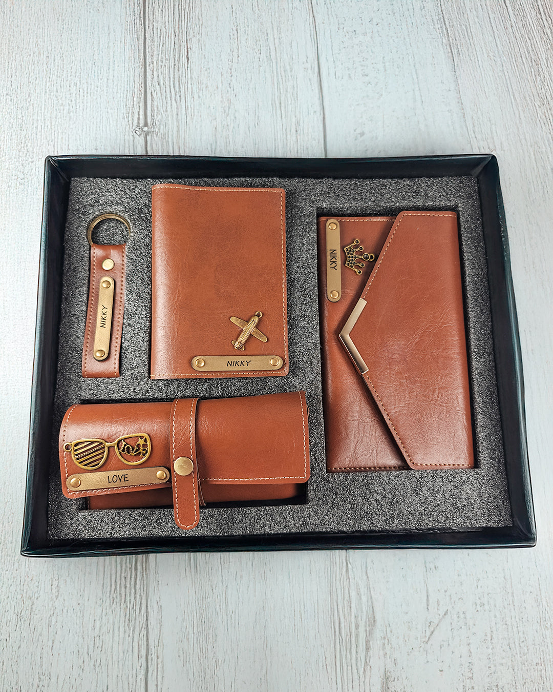 Set of brown leather wallets and keychains in a box on a light wooden surface