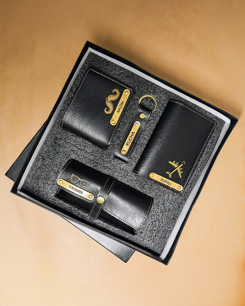 Black leather wallet and keychain set with gold accents in a box on a beige background