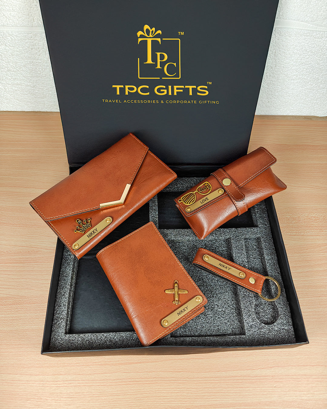 Set of brown leather wallets and keychains with gold accents in a TPC Gifts box.