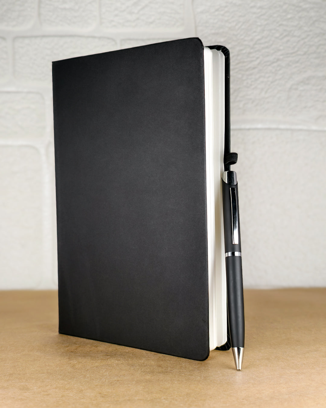 Black notebook and pen on a wooden surface with a light gray textured background