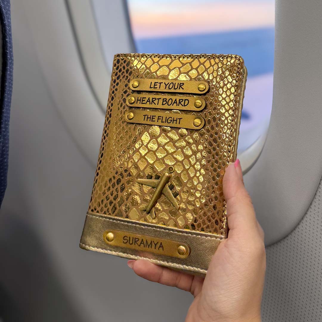 Gold textured passport holder with engraved text held by a hand, airplane window in the background