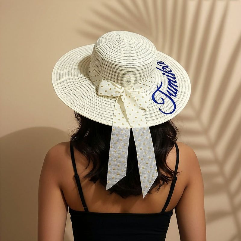 White sun hat with a decorative bow and text on a beige background