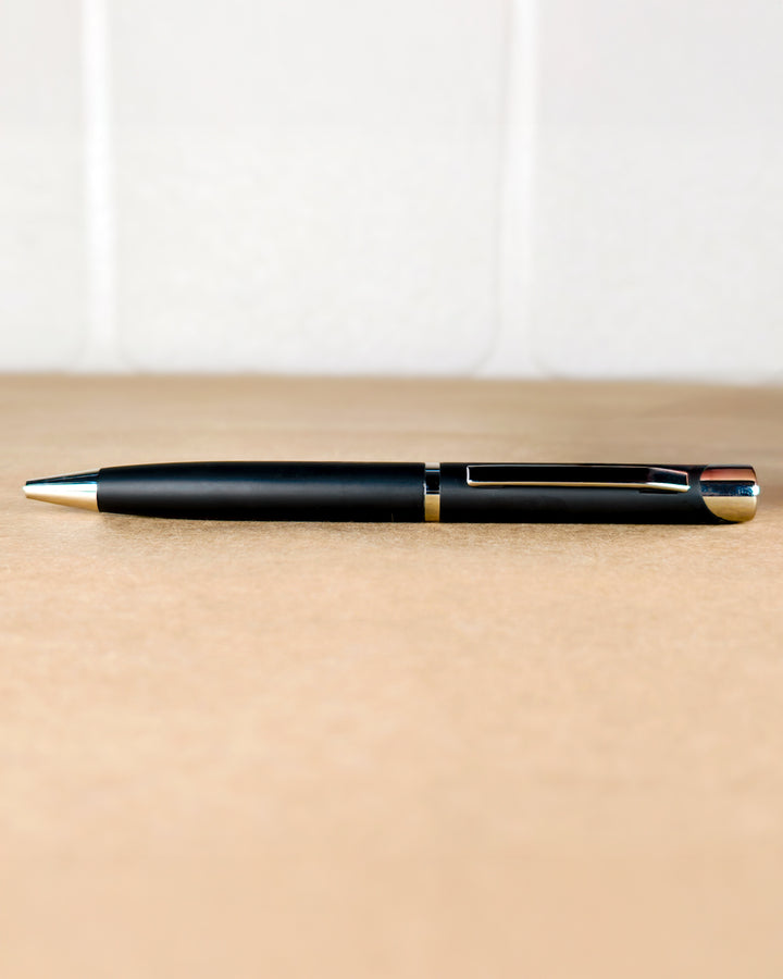 Black pen with gold accents on a beige surface