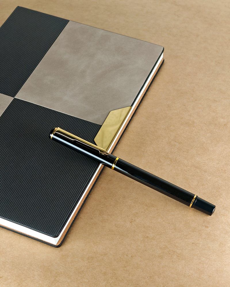 Black and gold pen on a checkered notebook with a brown background