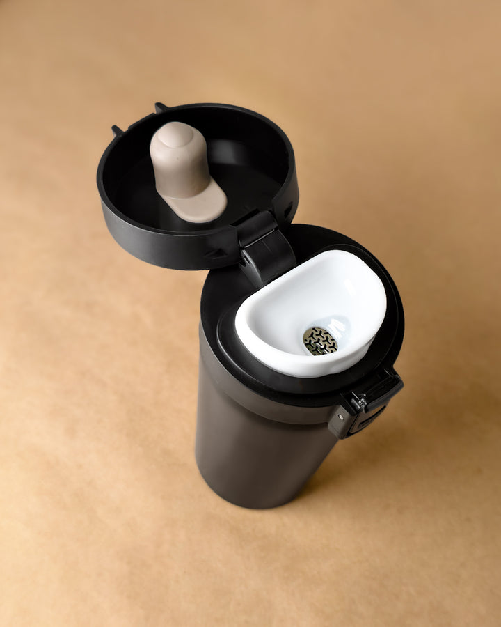 Black travel mug with a white interior on a beige background