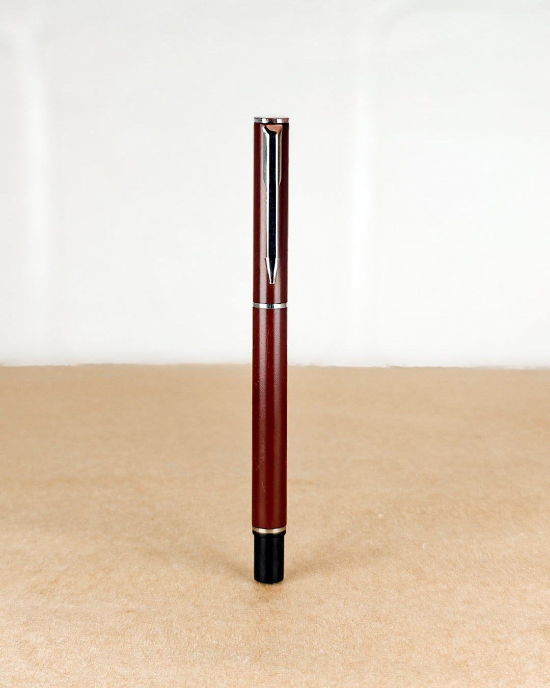 Red pen with a black cap on a beige surface and white background