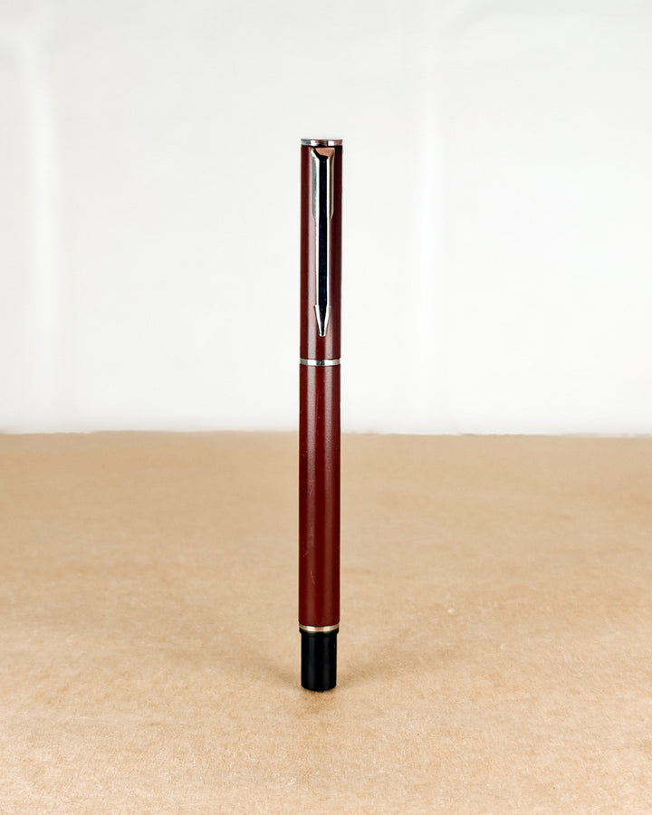 Red pen with a black cap on a beige surface and white background