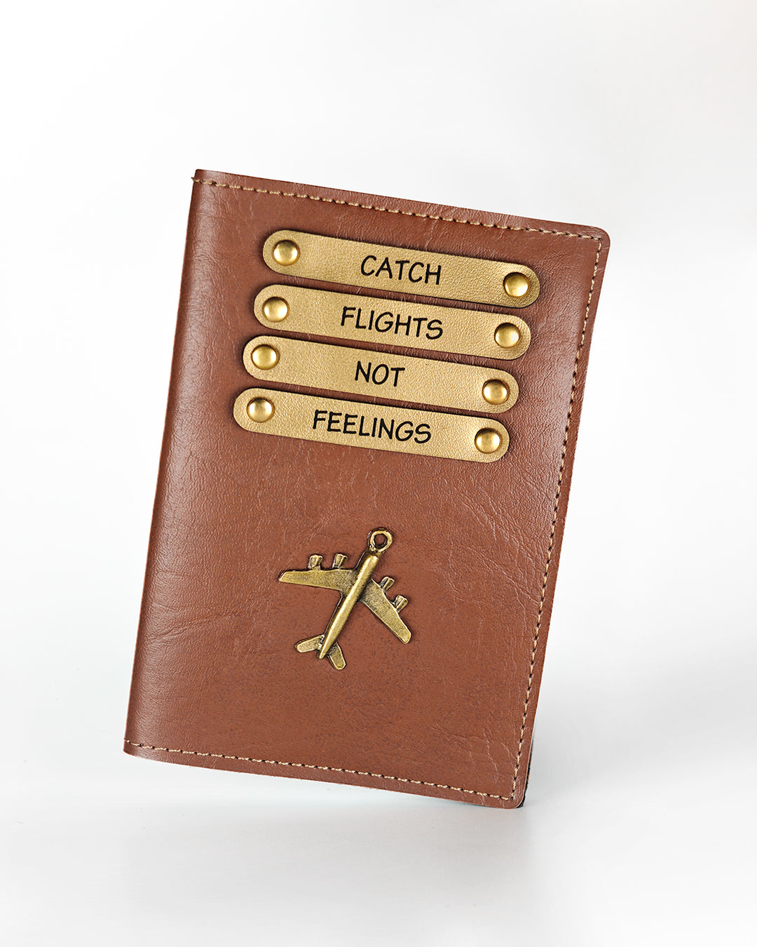 Brown leather passport cover with gold accents and motivational quote on a white background