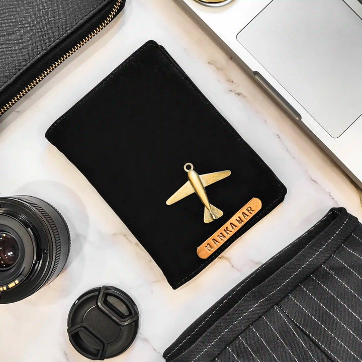 A black velvet passport cover with a gold airplane charm and a personalized wooden nameplate reading &