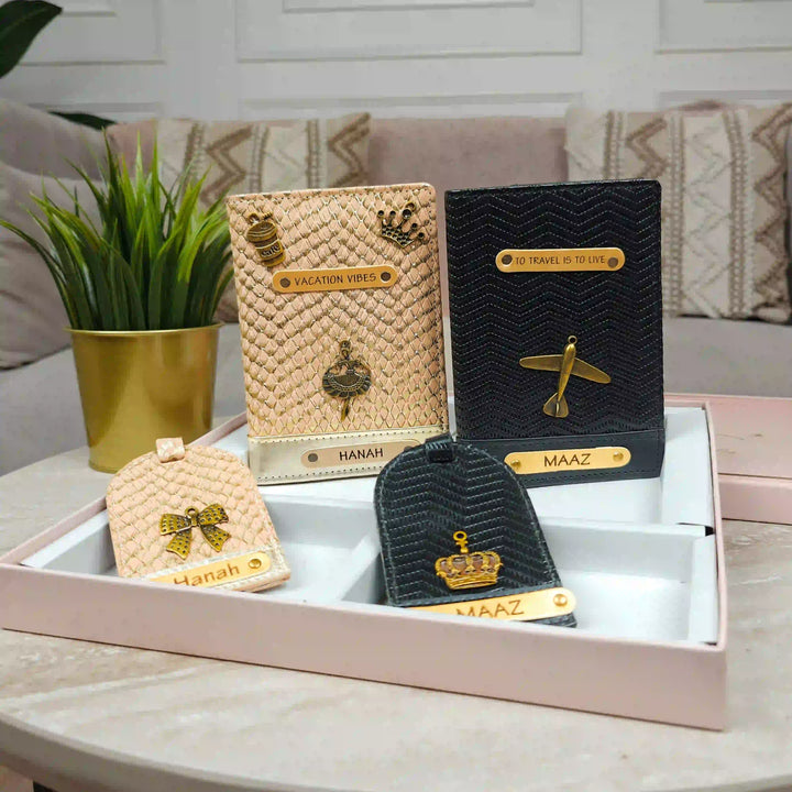 A set of personalized luggage tags and passport covers displayed in a pink presentation box on a marble table, with a potted plant and sofa in the background.