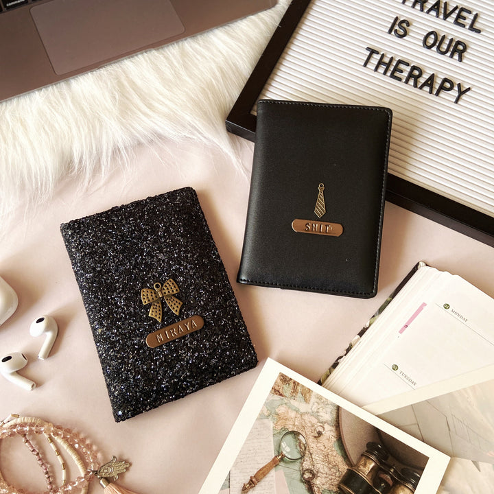 A collection of personal items including a sparkling  couple black passport cover, a laptop, a notebook, a framed sign reading &