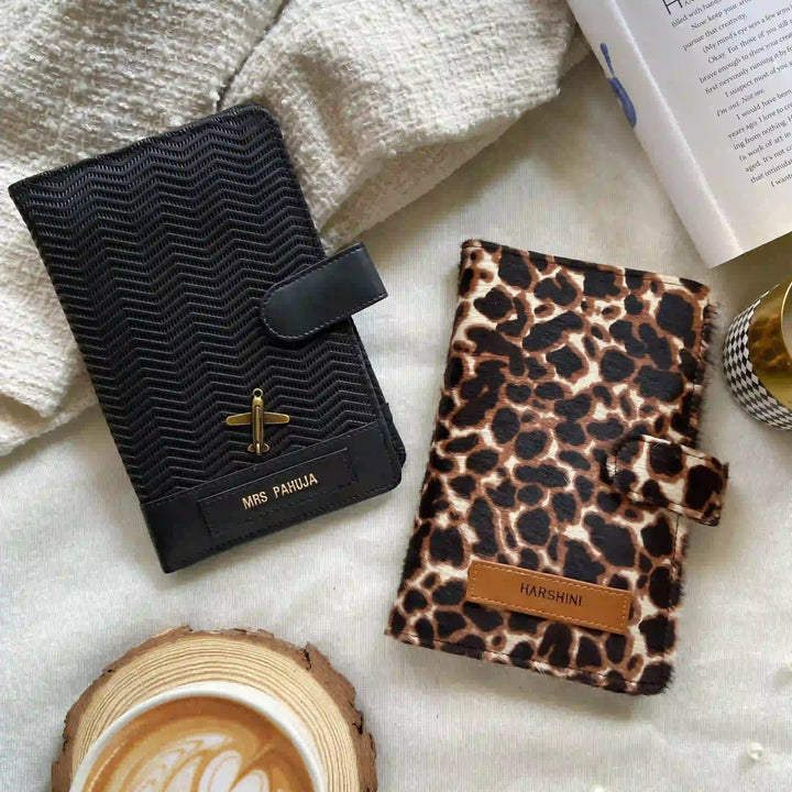 Black textured notebook with gold accents and a leopard print notebook on a light surface with a coffee cup and book.