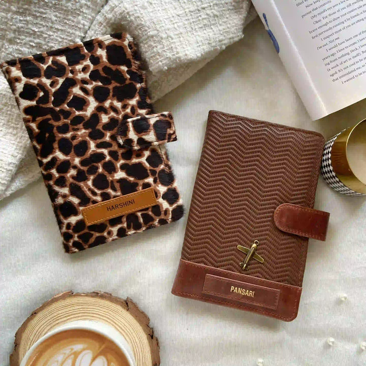 Two leather-bound books with distinctive covers on a textured surface with a cup of coffee.