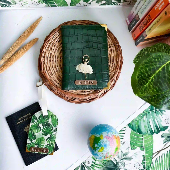 A dark green crocodile-embossed passport cover with a white ballerina charm and a gold &