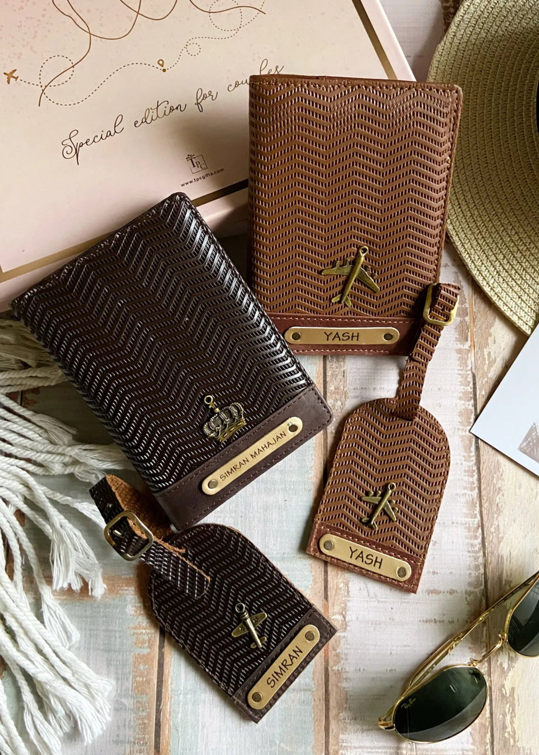 A set of couple passport covers and luggage tags with a wavy texture design in light brown and dark brown colors, displayed alongside travel-related items like a hat and sunglasses.