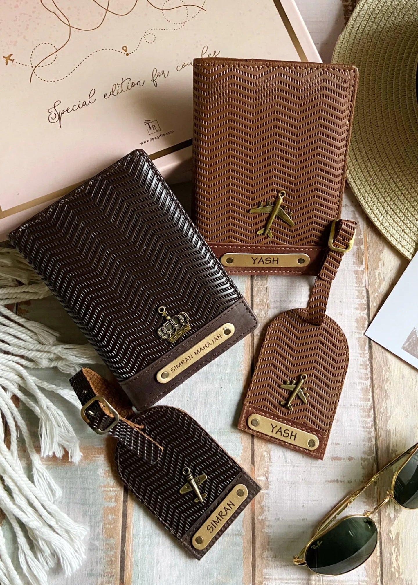 A set of couple passport covers and luggage tags with a wavy texture design in light brown and dark brown colors, displayed alongside travel-related items like a hat and sunglasses.
