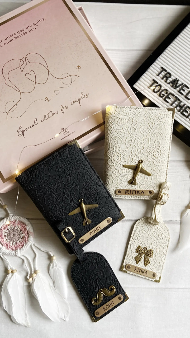 Two passport covers and two luggage tags with personalized engravings, one in black and one in a pastel color, displayed on a table with a pink gift box and a note reading &