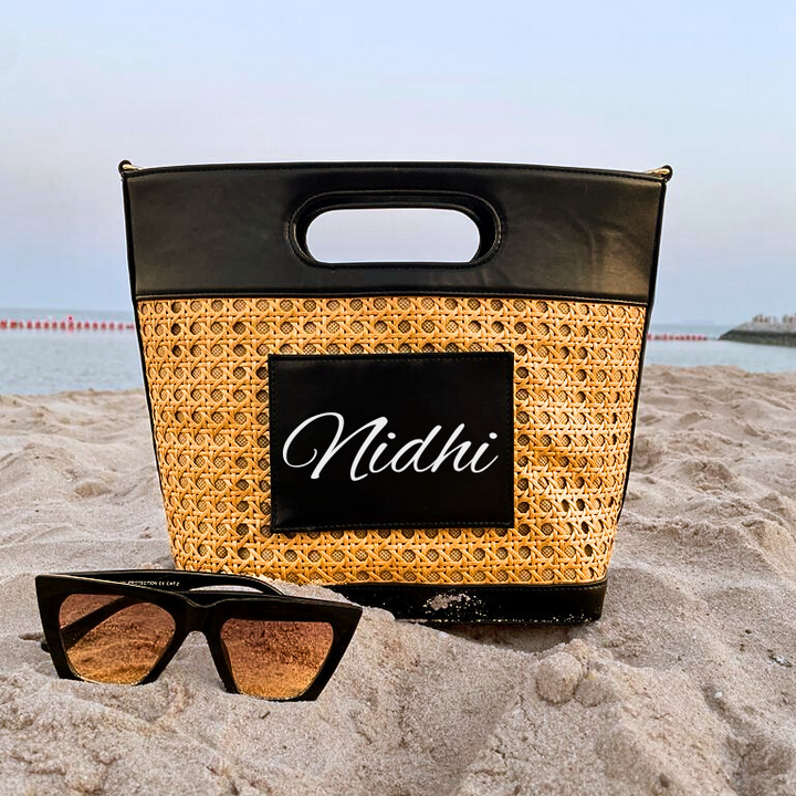 A personalized black cane beach bag with the name &