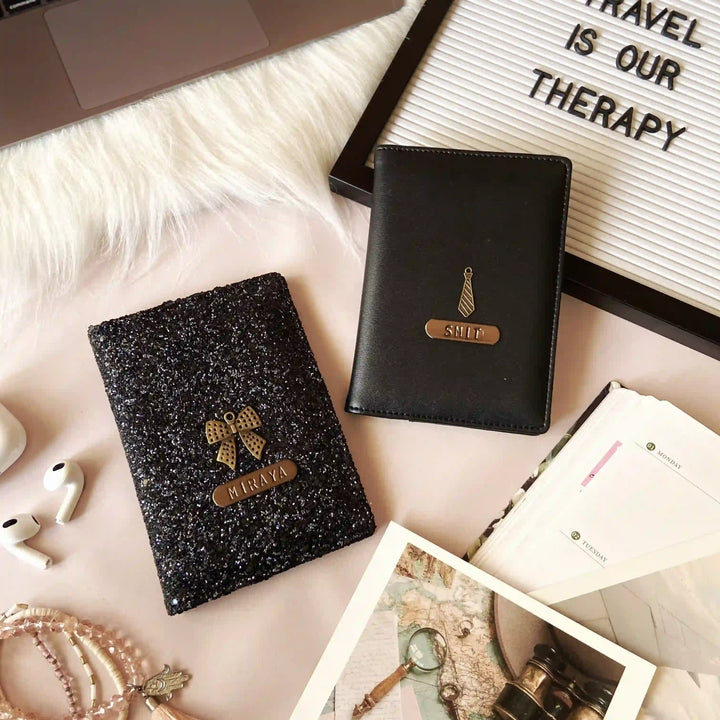 A collection of personal items including a sparkling  couple black passport cover, a laptop, a notebook, a framed sign reading &