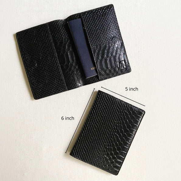 Black textured leather passport holder wallet shown open and closed on a light background, with dimension labels indicating 5 inch width, 6 inch height, and a navy blue interior slot.