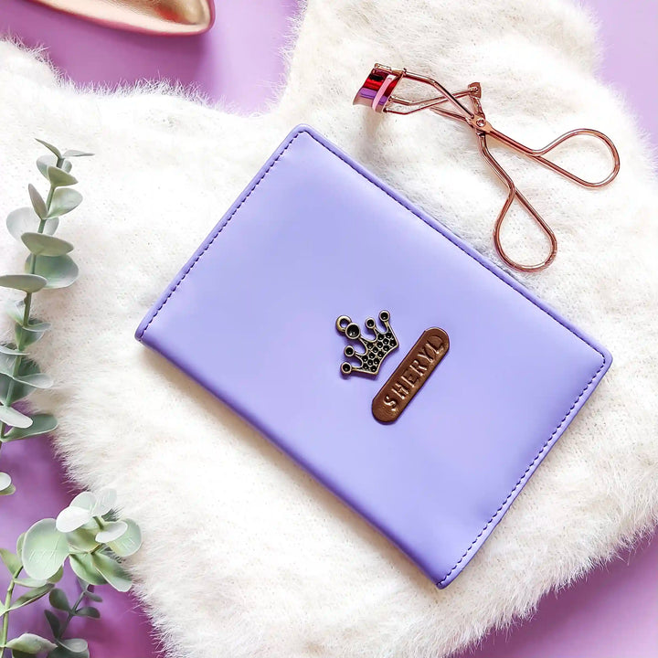 A purple vegan leather passport cover with a faux fur lining, a passport partially inserted, and a name tag on the cover, placed on a purple surface with a decorative item in the background.