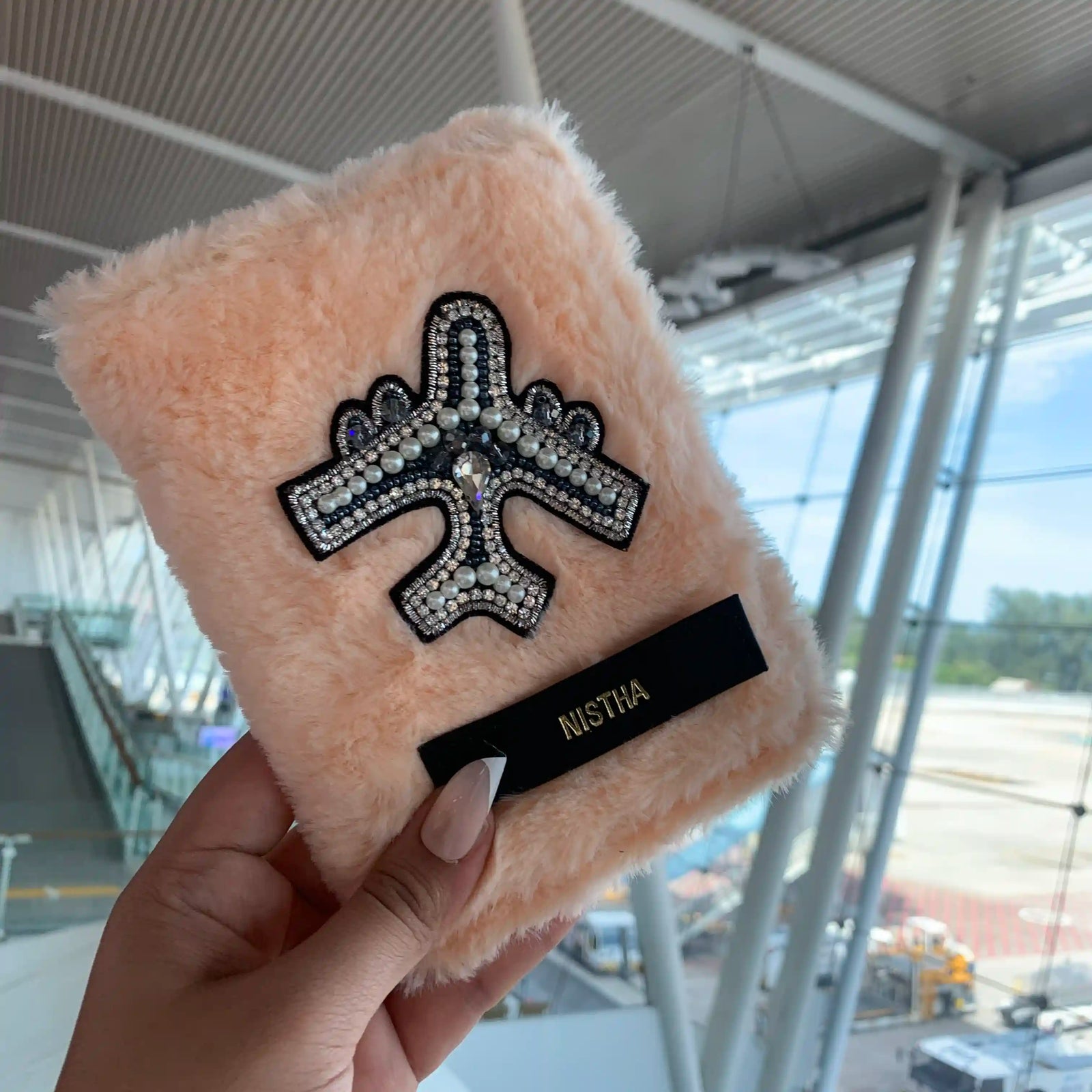 Salmon furr passport cover held in hand at the airport - TPC Gifts