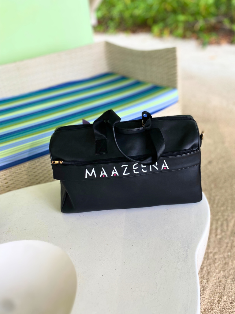Personalized Travel Duffle Bag - Elegant Black Leather on a beach with the name mazeena on it. 