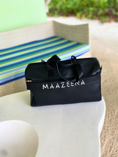 Personalized Travel Duffle Bag - Elegant Black Leather on a beach with the name mazeena on it. 