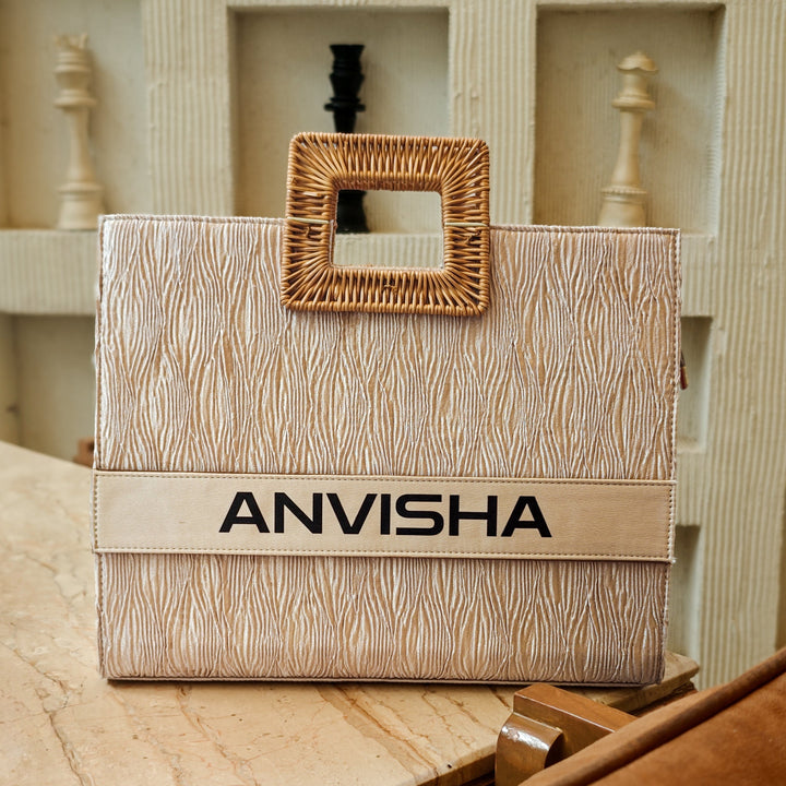 A beige tote bag with a square cane handle and text pattern, placed on a marble surface, with the brand name &