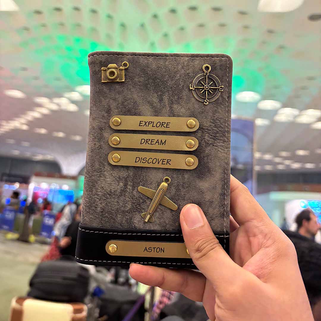 Hand holding a passport holder with decorative elements in an airport setting