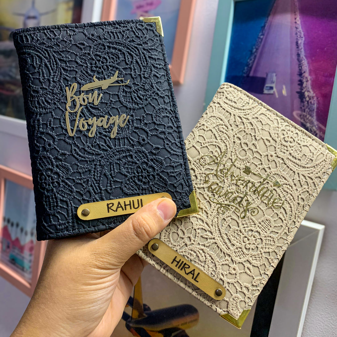 Two people holding black and white couple passport covers with custom text and charms, displayed in an airport setting.