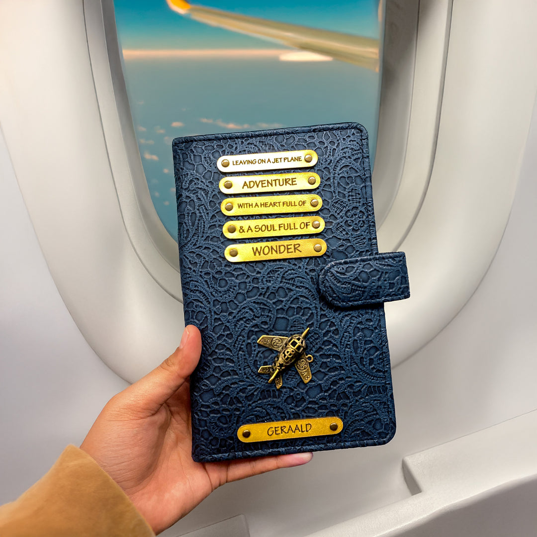 Blue passport holder with gold text and emblem held in front of an airplane window