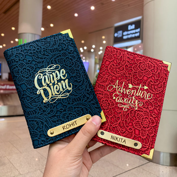 Two people holding black and white passport covers by TPC Gifts with custom text and charms, displayed in an airport setting.