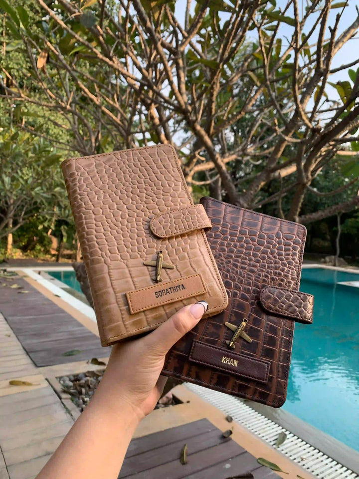 Two leather travel organizers held in hands, one in front and one in back, displaying crocodile pattern, in brown  colors - TPC Gifts