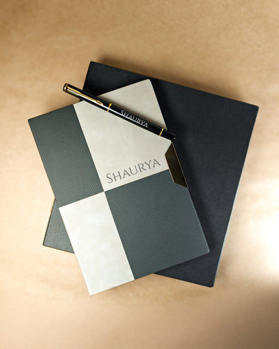 Notebook and pen set with 'SHAUURYA' branding on a beige background