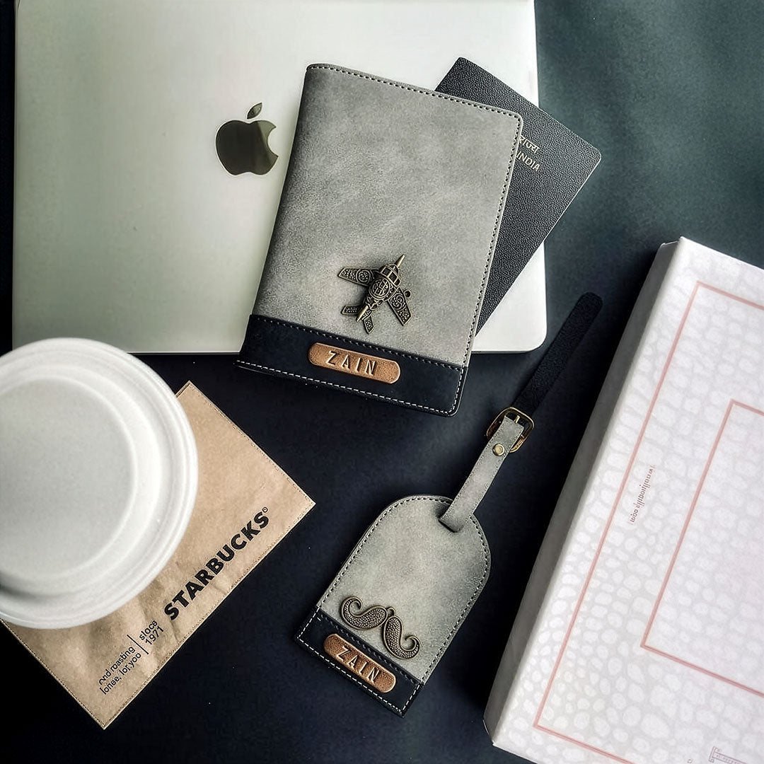 Gray leather passport holder with airplane emblem and 'Zain' branding on a desk with Starbucks cup and laptop.