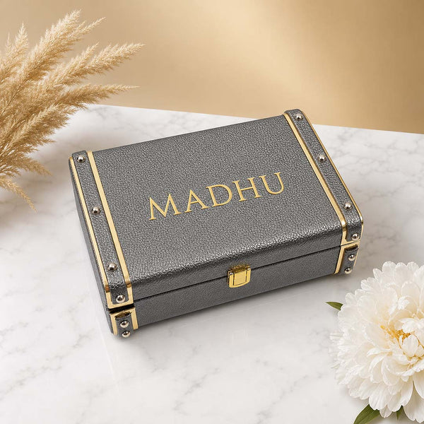 Gray trunk box with 'MADHU' name on a marble surface with flowers and pampas grass from TPC Gifts