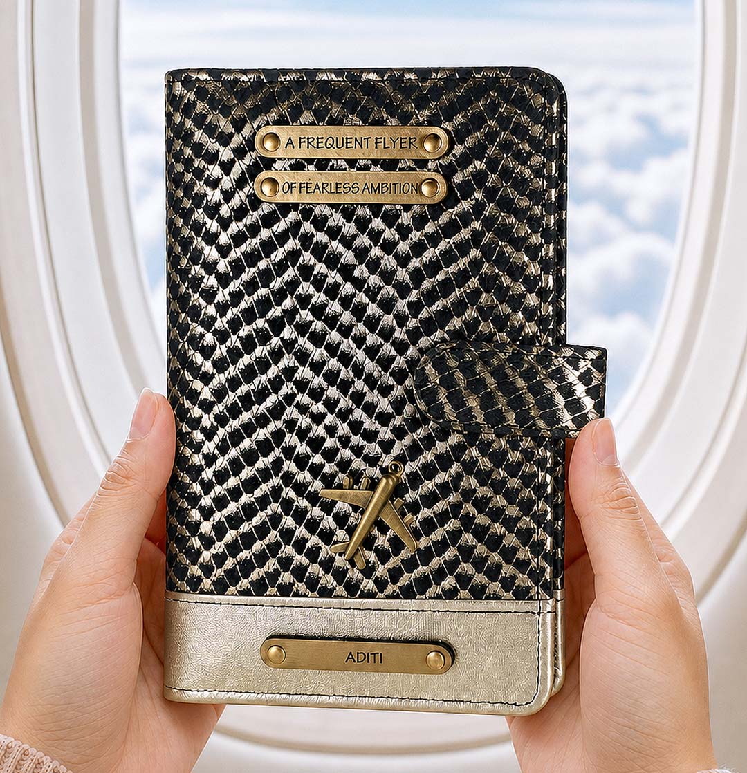 Patterned passport holder with gold accents held by hands against a blurred window background