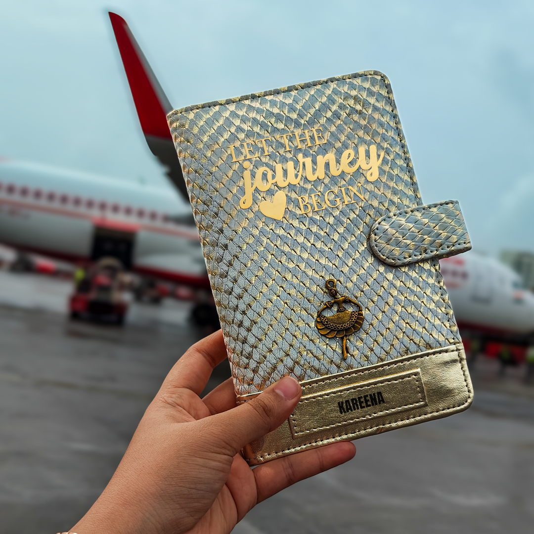 A personalized travel wallet by TPC Gifts with gold and ivory colors, featuring text and a crest design, held in a person&