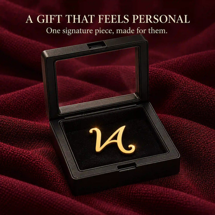 Gold tone script initial lapel pin in a black presentation box