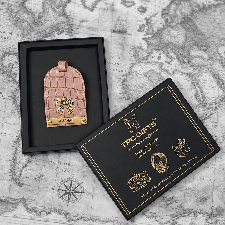 Pink crocodile-patterned luggage tag with gold accents in a black box on a world map background